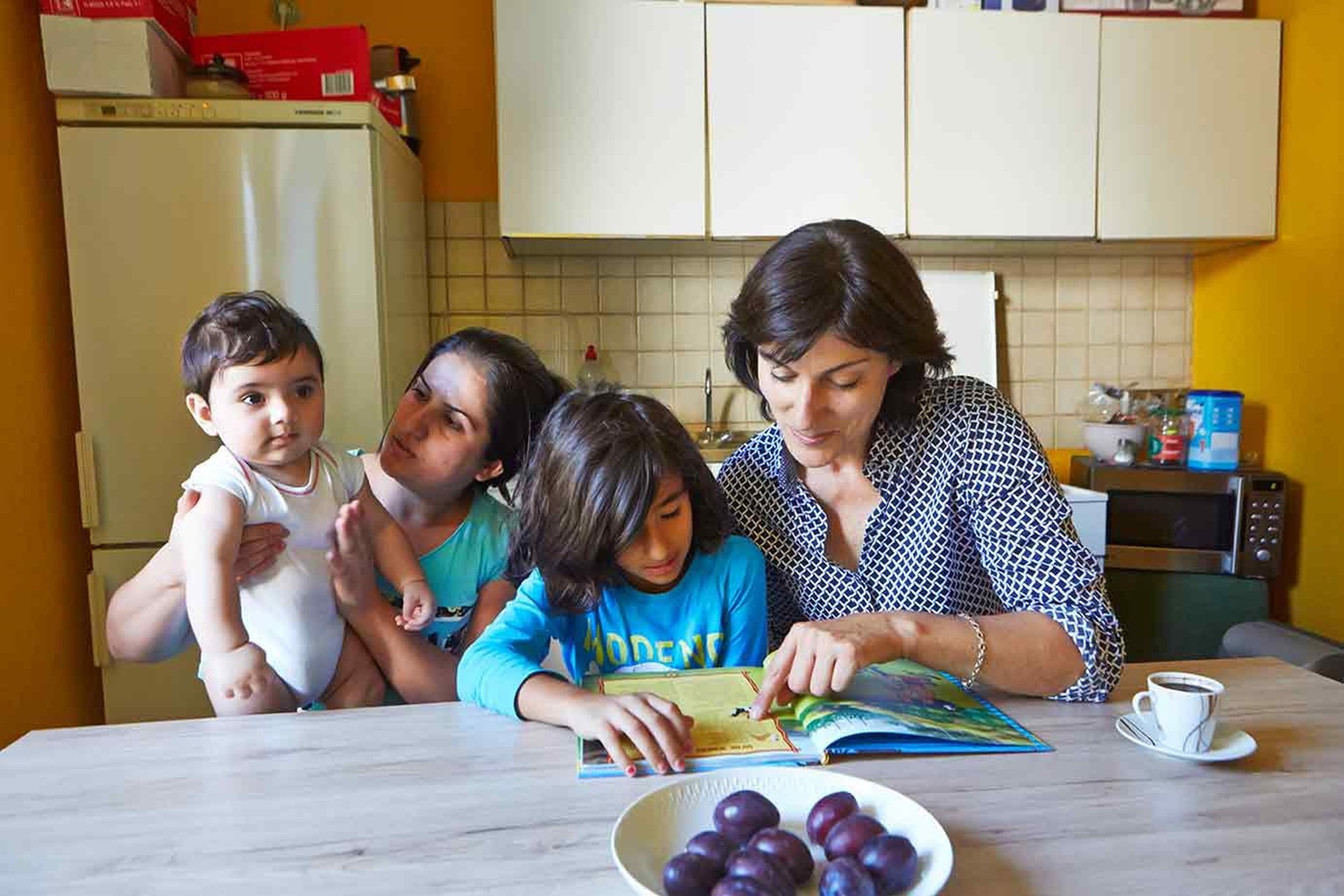 Zwei Frauen, ein Kind und ein Baby am Küchentisch.